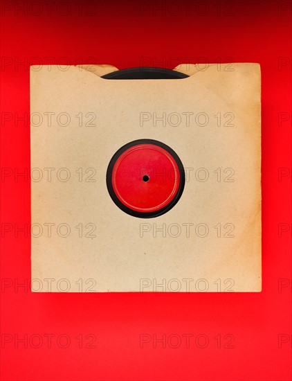 Vinyl record in envelope on red background, studio shot.
