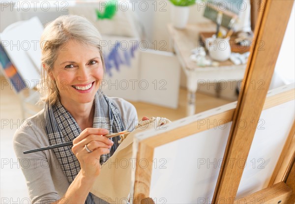 Portrait of senior woman painting on canvas.