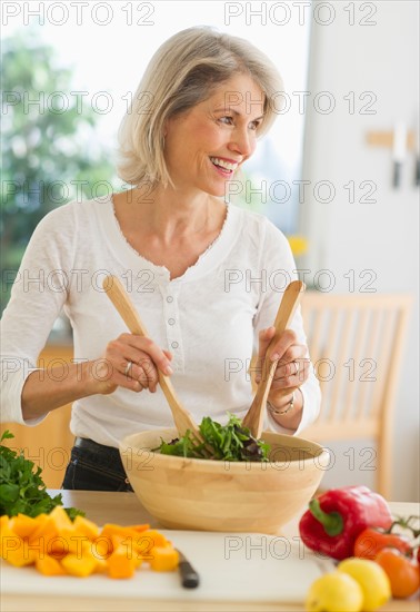 JPortrait of senior woman preparing salad in kitchen.