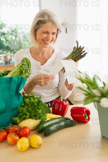 Portrait of senior woman with shopping bag in kitchen.