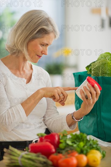 Portrait of senior woman checking product in kitchen.