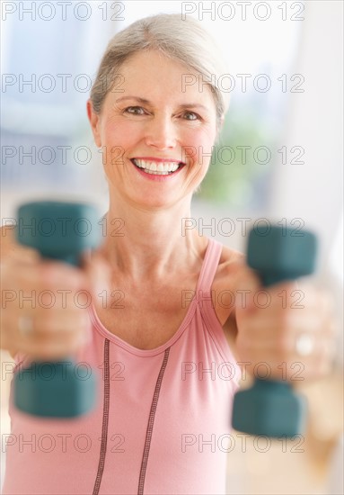 Portrait of senior woman exercising with dumbbells in gym.