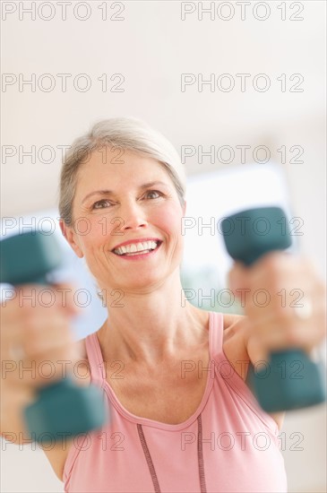 Portrait of senior woman exercising with dumbbells in gym.