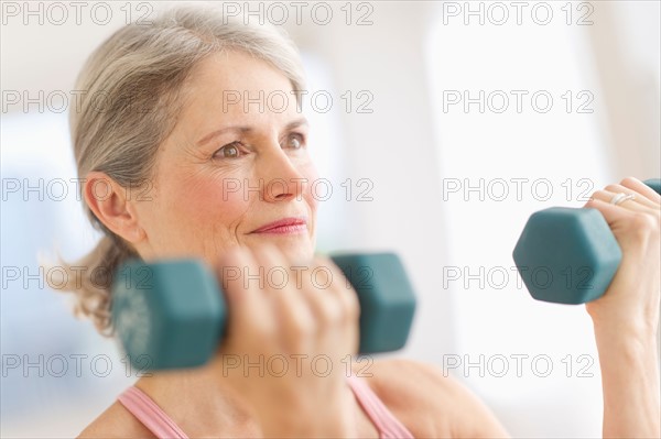 Portrait of senior woman exercising with dumbbells in gym.