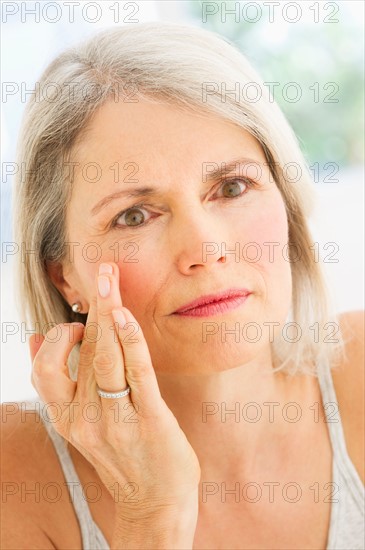 Portrait of senior woman applying moisturizer.