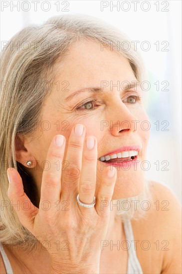 Portrait of senior woman applying moisturizer.