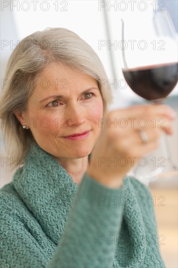 Senior female connoisseur tasting red wine.