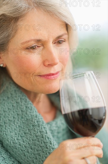 Senior female connoisseur tasting red wine.