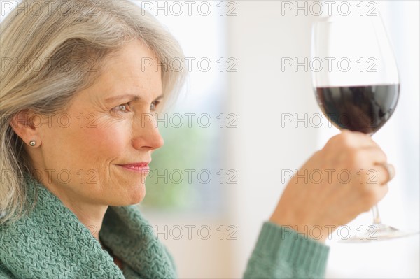 Senior female connoisseur tasting red wine.