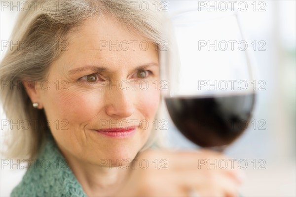 Senior female connoisseur tasting red wine.