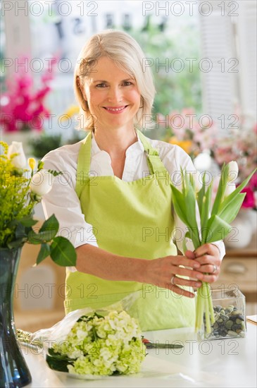 Senior female florist arranging bouquet.