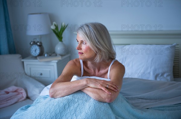 Senior woman sitting in bed and suffering from insomnia.