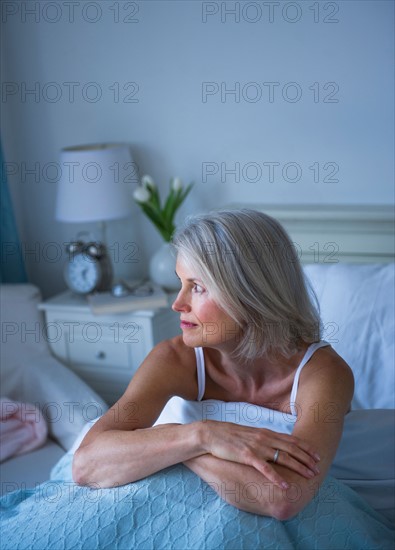 Senior woman sitting in bed and suffering from insomnia.