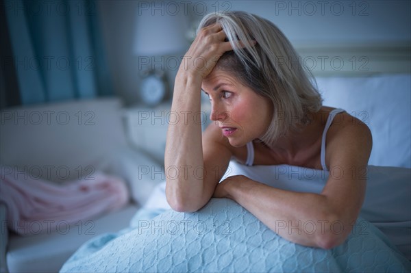 Senior woman sitting in bed and suffering from insomnia.