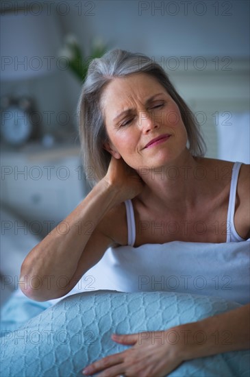 Senior woman sitting in bed and suffering from necklace.