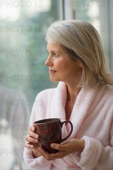 Senior woman looking through window in morning.