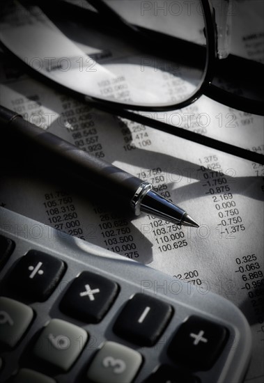 Close up of pen, glasses and calculator, studio shot.