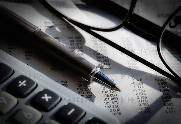 Close up of pen, glasses and calculator, studio shot.