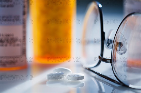 Close up of glasses and pills on white background, studio shot.