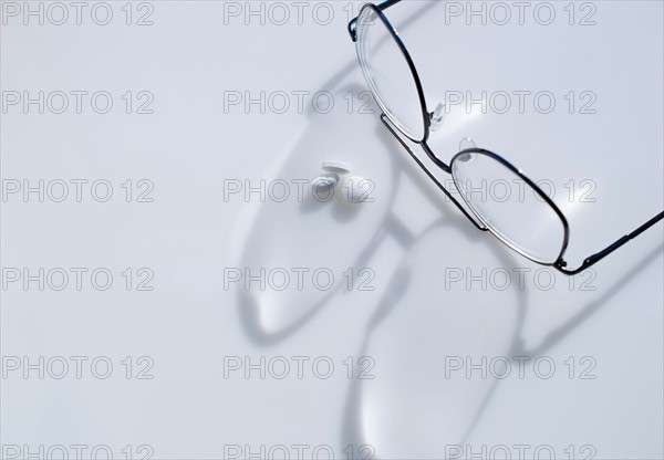 Close up of glasses and pills on white background, studio shot.