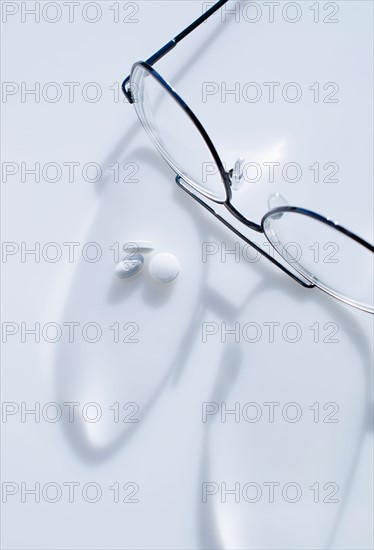 Close up of glasses and pills on white background, studio shot.