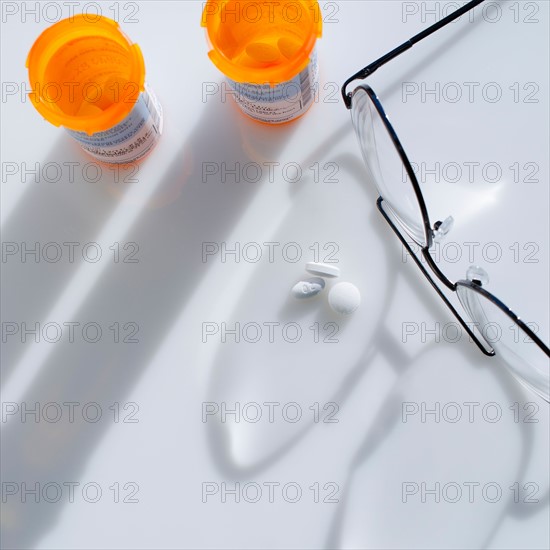 Close up of glasses and pills on white background, studio shot.