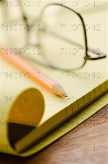 Close up of glasses, notebook and pencil, studio shot.