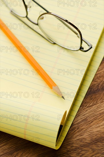 Close up of glasses, notebook and pencil, studio shot.