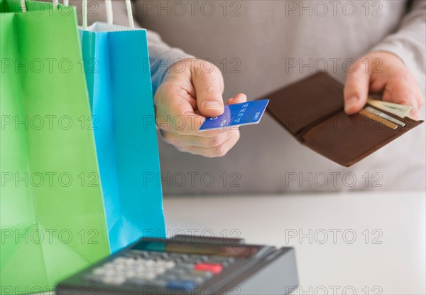 Close up of man's hands holding credit card and wallet, studio shot.