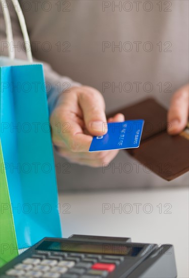 Close up of man's hands holding credit card and wallet, studio shot.