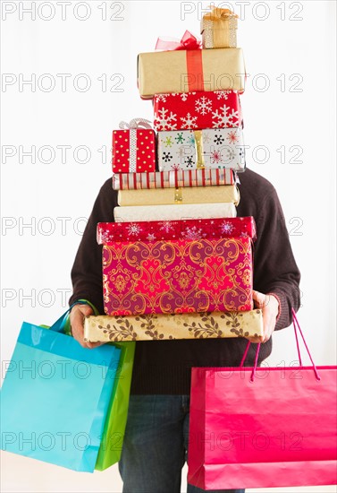 Man carrying stack of Christmas presents, studio shot.