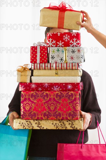 Man carrying stack of Christmas presents, studio shot.