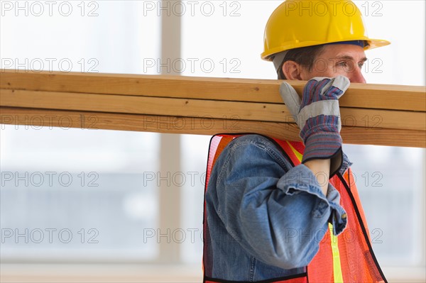 Construction worker carrying planks.