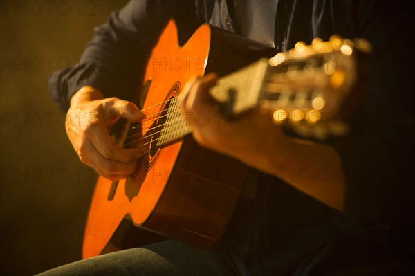 Close up of man playing acoustic guitar, studio shot.