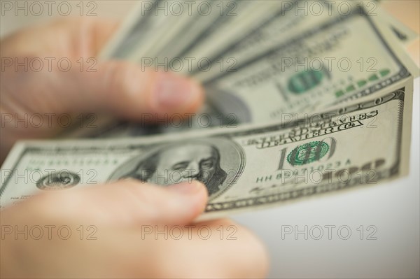 Close up of man's hands counting dollar banknotes.