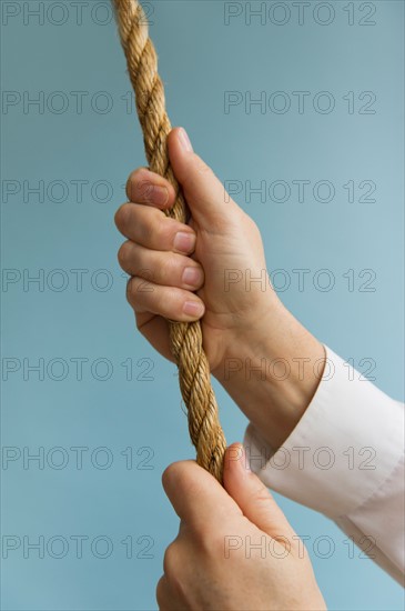 Close up of man's hands pulling rope, studio shot.