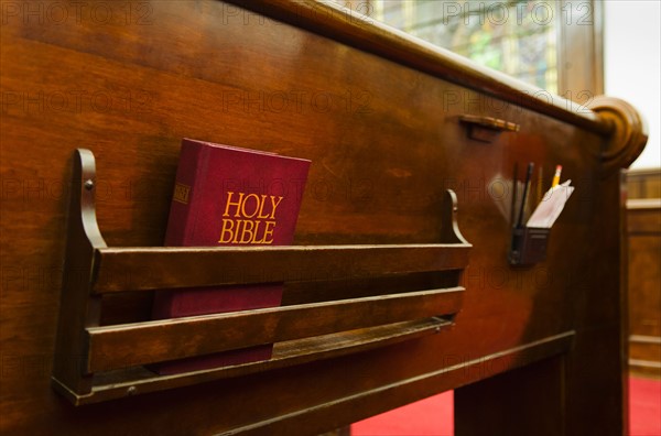 Close up of bible on wooden church pew.
