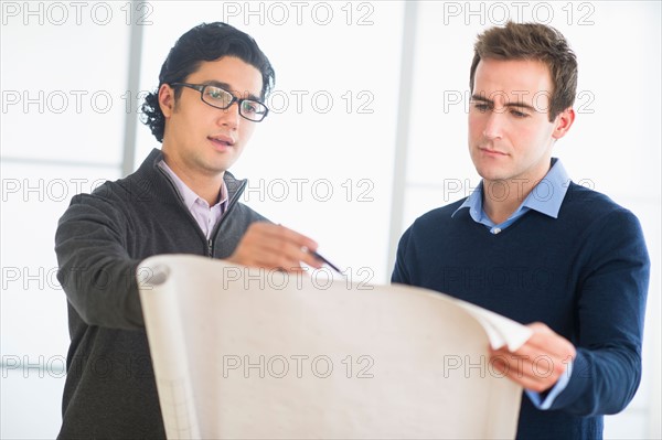 Two businessmen discussing blueprint.