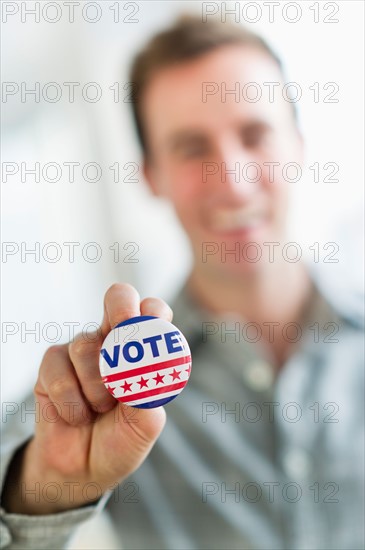 Close up of man's hand holding vote button.