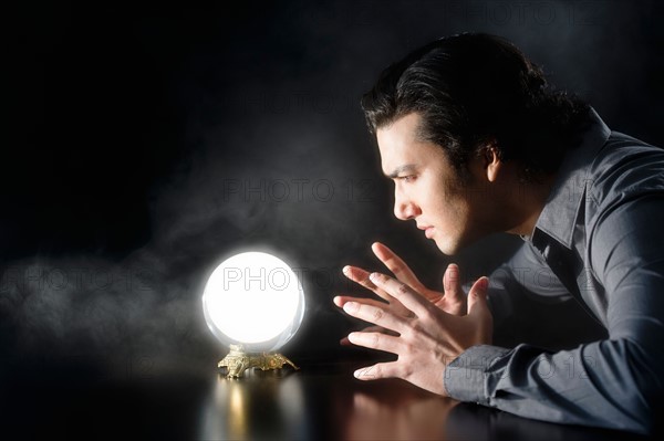 Studio shot of businessman looking at crystal ball.