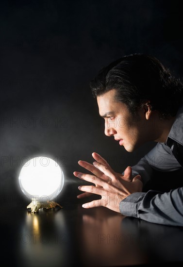 Studio shot of businessman looking at crystal ball.