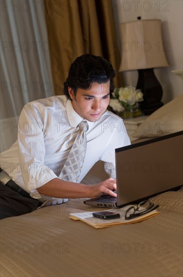 Businessman working on laptop in hotel room.