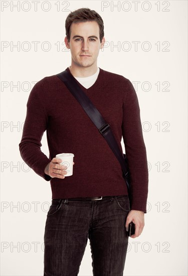 Studio shot of man holding coffee cup.