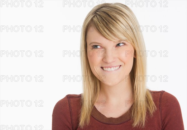 Studio portrait of woman smiling and biting lip.