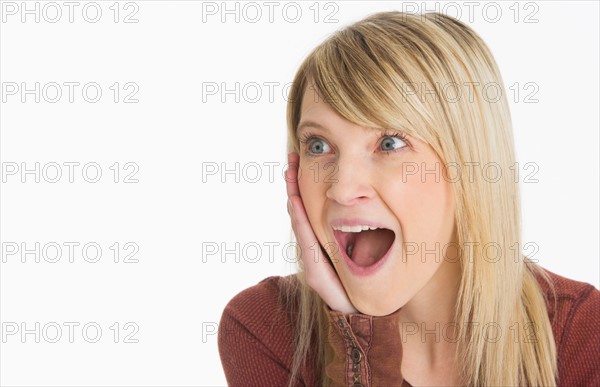 Studio portrait of woman looking surprised.