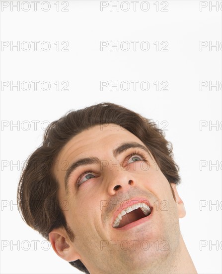 Studio portrait of man smiling and looking up.