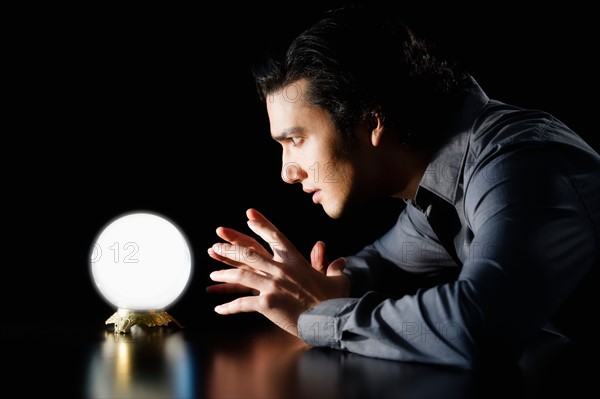 Studio shot of businessman staring at crystal ball.