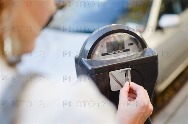 USA, New York State, New York City, Brooklyn, Woman inserting coin into parking meter. Photo : Jamie Grill