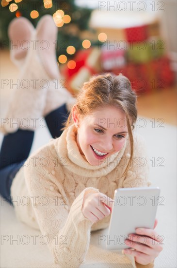 Portrait of young woman lying on floor with digital tablet. Photo : Daniel Grill