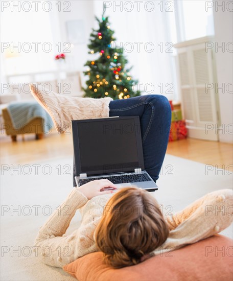 Young woman lying on floor with laptop. Photo : Daniel Grill